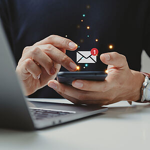 Mann hält ein Smartphone in den Händen. Darüber ist ein Email-Icon zu sehen.