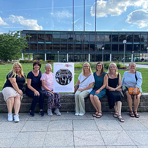 Mitarbeiterinnen der VHS Unterland vor dem Landtag in Stuttgart. Sie halten ein Plakat mit dem aktuellen Titelbild des Programmheftes in den Händen.