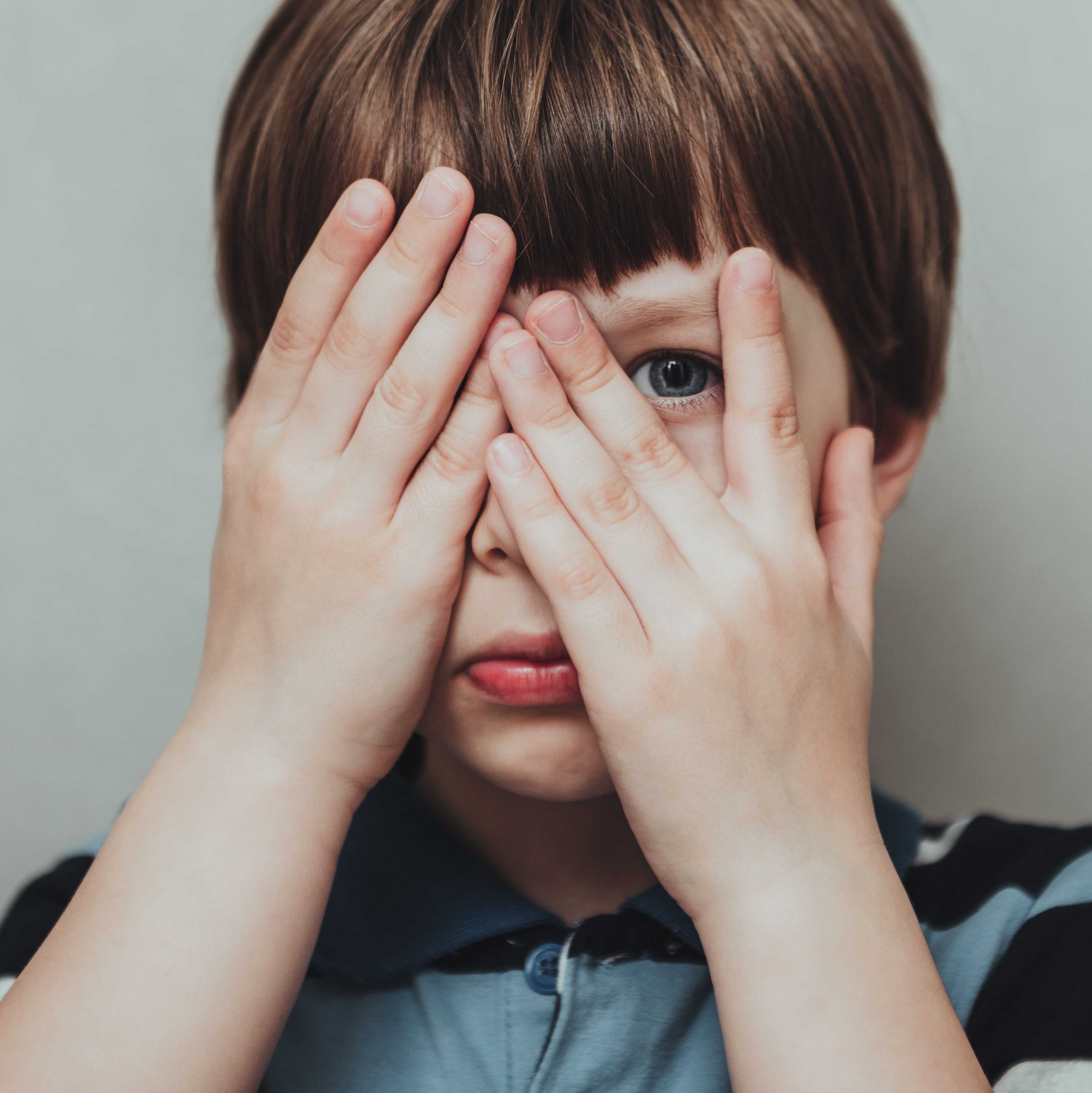 Kind hält sich die Augen zu und schaut hinter einem Finger hervor.