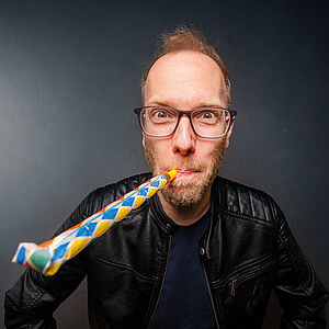 Comedian Michael Krebs mit einer Partytröte.