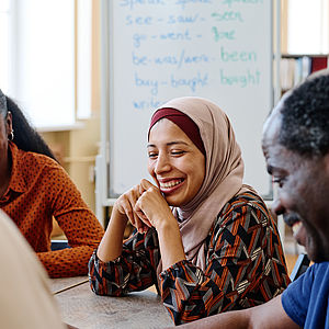 Menschen aus unterschiedlichen Kulturen sitzen am Tisch und lachen